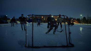 A group of people playing a casual pick-up game of hockey at dusk.