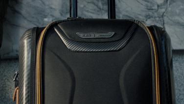 A close-up of a black and tan roller suitcase.
