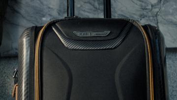 A close-up of a black and tan roller suitcase.