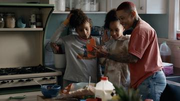 A black mother and her two teenage daughters taking a selfie in their kitchen.